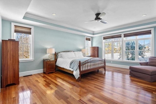 bedroom featuring light wood-style floors, a raised ceiling, and crown molding