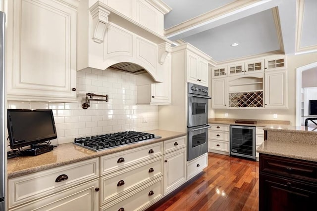 kitchen with wine cooler, appliances with stainless steel finishes, light stone countertops, dark wood-style floors, and glass insert cabinets