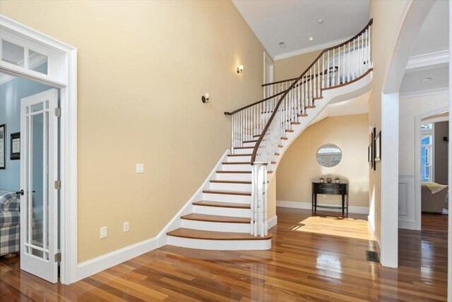 staircase featuring baseboards, wood finished floors, and ornamental molding