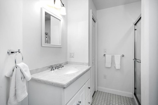 full bathroom with a stall shower, vanity, and baseboards