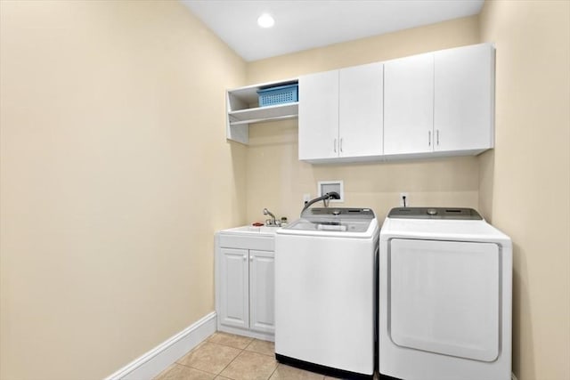 clothes washing area featuring washing machine and clothes dryer, light tile patterned floors, cabinet space, a sink, and baseboards