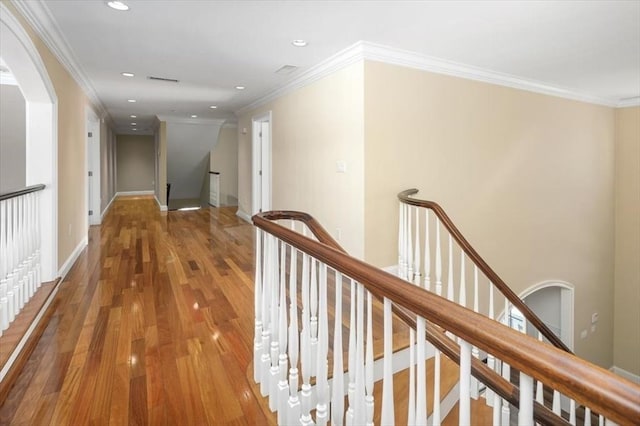 hallway featuring baseboards, wood finished floors, crown molding, an upstairs landing, and recessed lighting