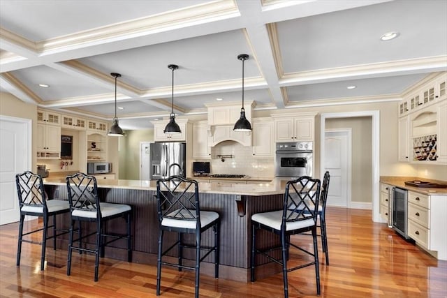 kitchen with stainless steel appliances, light countertops, light wood-type flooring, premium range hood, and a kitchen breakfast bar