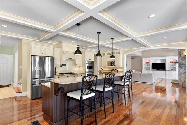 kitchen with a breakfast bar, appliances with stainless steel finishes, light countertops, and cream cabinetry