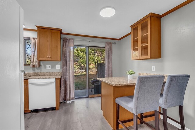 kitchen with light stone countertops, dishwasher, light hardwood / wood-style flooring, crown molding, and a kitchen bar