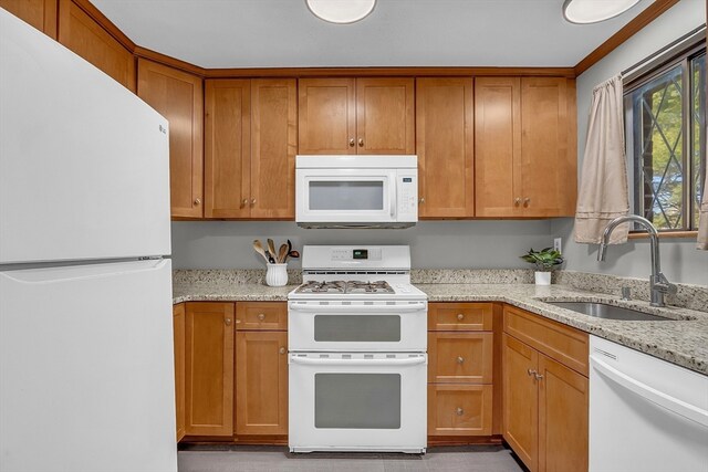 kitchen with white appliances, light stone counters, and sink