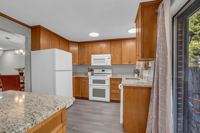 kitchen featuring light stone countertops, sink, an inviting chandelier, light hardwood / wood-style flooring, and white appliances