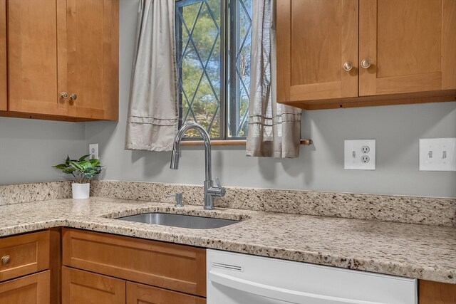 kitchen with dishwasher, sink, and light stone counters