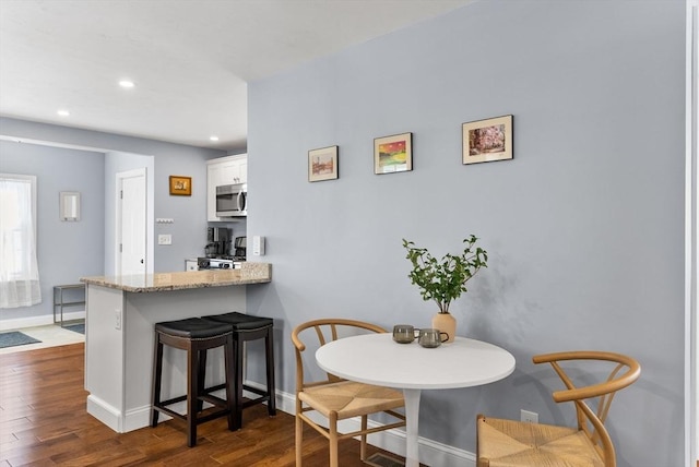 dining space featuring dark wood-style floors, baseboards, and recessed lighting