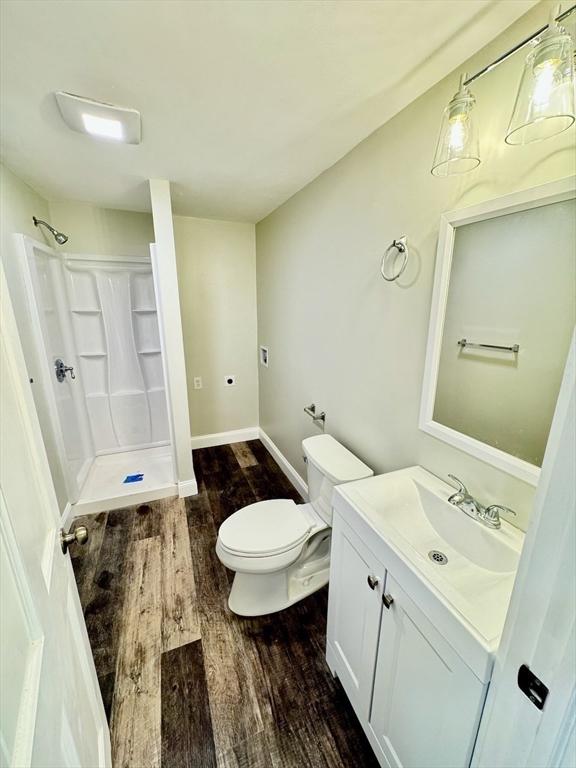 bathroom featuring hardwood / wood-style floors, a shower, toilet, and vanity