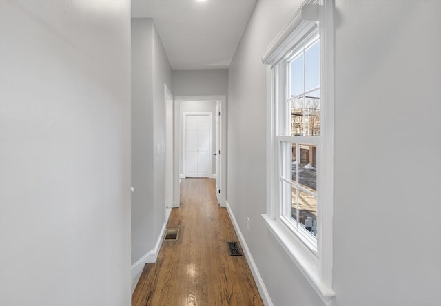 corridor with visible vents, baseboards, and wood finished floors