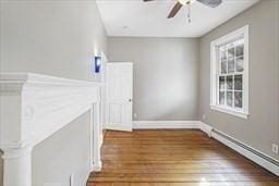 interior space with a baseboard radiator, a healthy amount of sunlight, ceiling fan, and dark hardwood / wood-style flooring