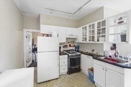 kitchen featuring white refrigerator, range with electric stovetop, sink, and white cabinets