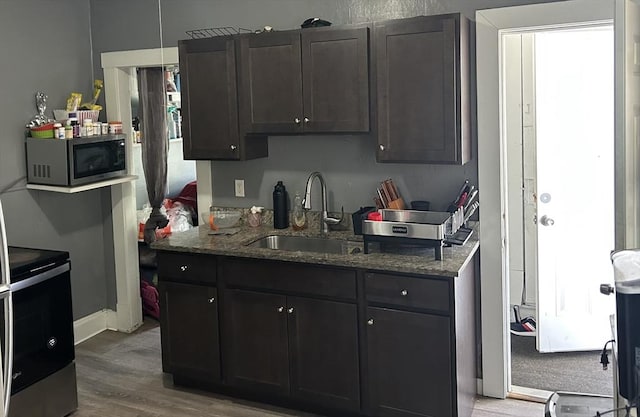 kitchen featuring a sink, dark stone countertops, appliances with stainless steel finishes, and wood finished floors