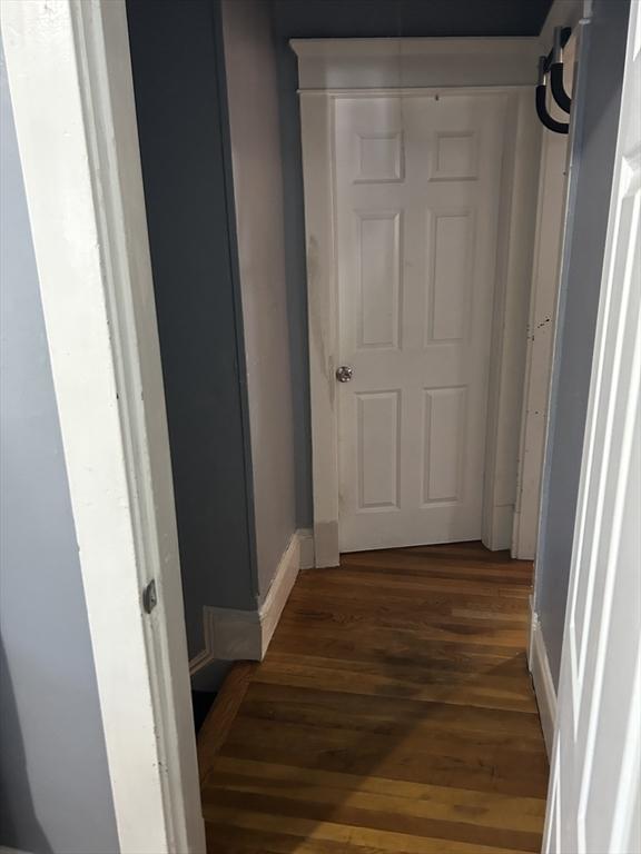 corridor featuring baseboards and wood finished floors