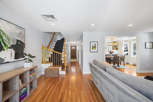 living area with baseboards, visible vents, stairway, light wood-type flooring, and recessed lighting