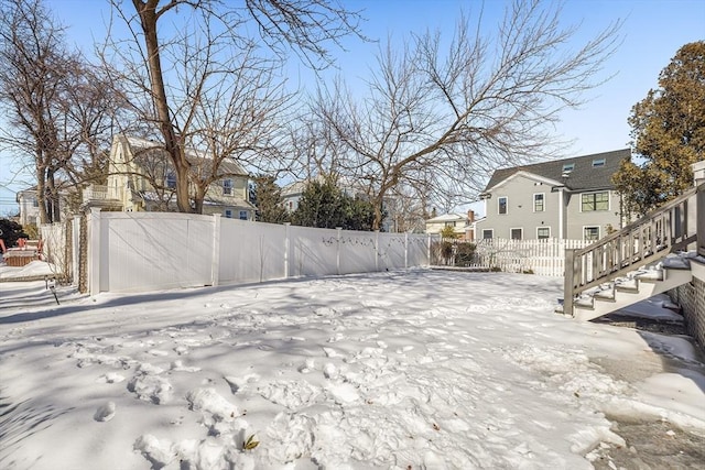 yard layered in snow with stairway, a residential view, and fence