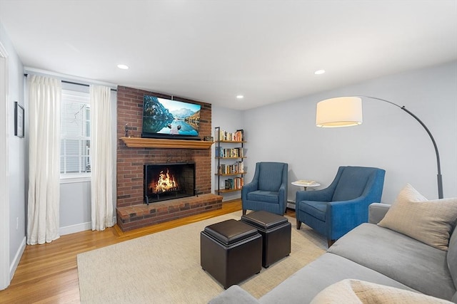 living area with light wood finished floors, a brick fireplace, recessed lighting, and baseboards