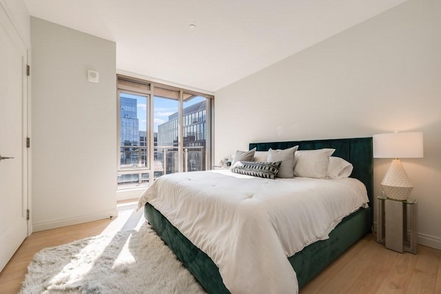 bedroom featuring a view of city, baseboards, and light wood finished floors