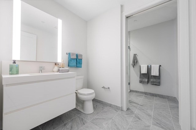 full bath featuring vanity, baseboards, a stall shower, and toilet