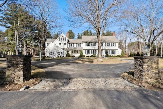 view of front facade featuring decorative driveway and a chimney