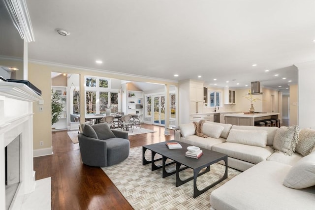 living room with a premium fireplace, wood-type flooring, ornamental molding, and ornate columns