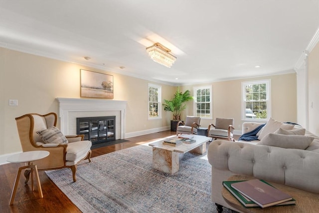 living area with baseboards, a fireplace with flush hearth, wood finished floors, and crown molding