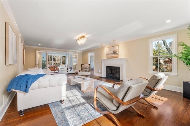 living room featuring a fireplace with flush hearth, wood finished floors, baseboards, and ornamental molding