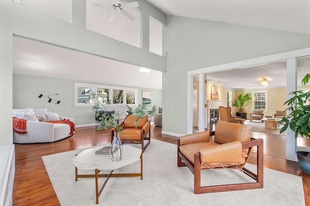 living room featuring a ceiling fan, wood finished floors, a fireplace, and baseboards