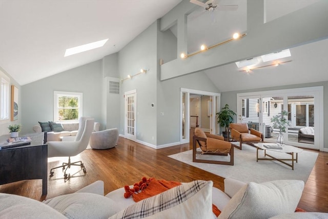 living area featuring high vaulted ceiling, wood finished floors, french doors, a skylight, and baseboards