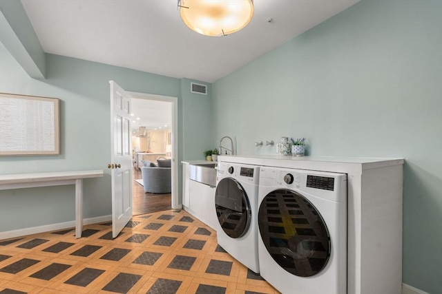 laundry room with visible vents, baseboards, cabinet space, and washing machine and clothes dryer