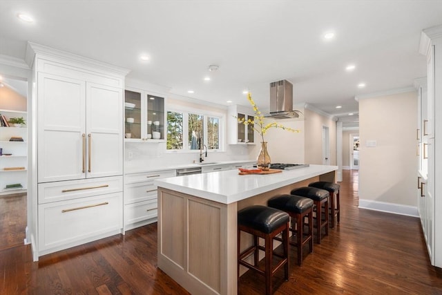 kitchen featuring a kitchen island, ventilation hood, glass insert cabinets, and light countertops