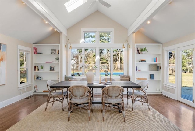 dining space featuring a skylight, baseboards, built in shelves, and wood finished floors