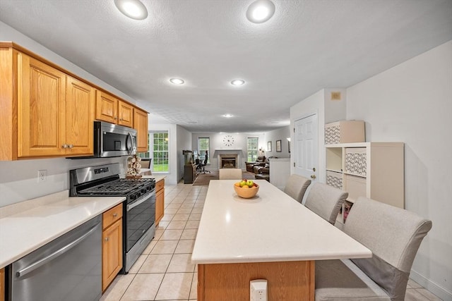 21 Butterfield Ln, Westford, MA 01886 - kitchen featuring stainless steel appliances, open floor plan, light countertops, a center island, and light tile patterned floors