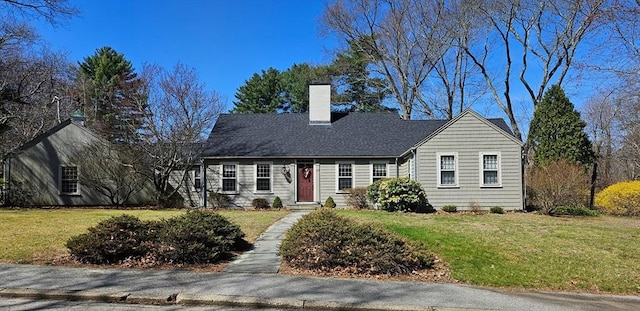 new england style home featuring a front yard and a chimney