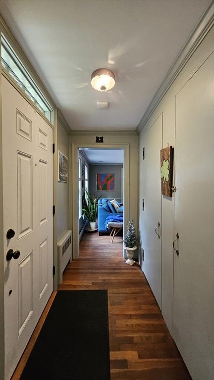 corridor featuring radiator heating unit, wood finished floors, and crown molding