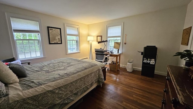 bedroom with multiple windows, wood finished floors, baseboards, and baseboard heating