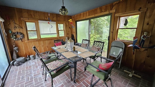 dining room with wood walls and brick floors