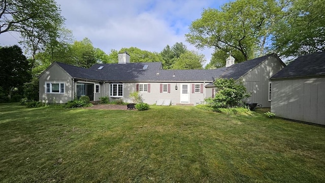 back of house featuring a chimney and a lawn