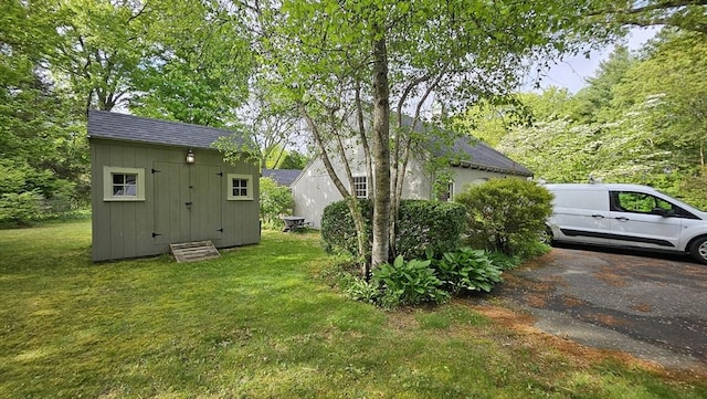 view of grassy yard with a storage shed and an outbuilding