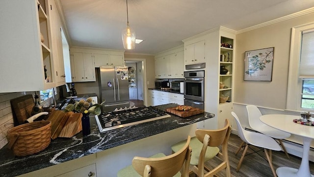 kitchen with appliances with stainless steel finishes, a peninsula, a warming drawer, dark countertops, and white cabinets