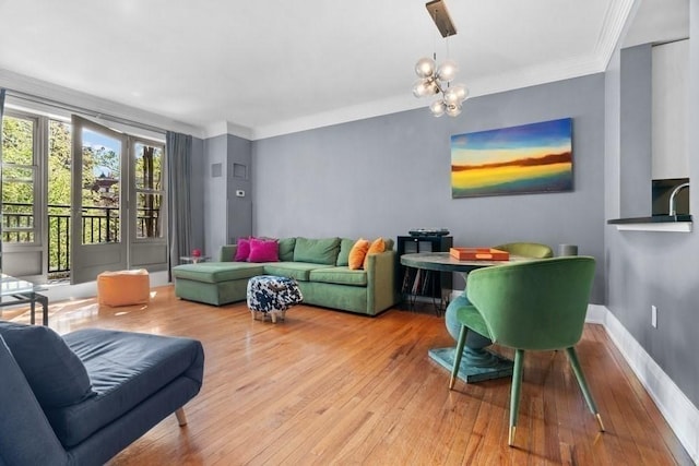 living room featuring crown molding, baseboards, wood-type flooring, and a chandelier