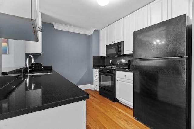 kitchen with dark countertops, white cabinetry, a sink, light wood-style flooring, and black appliances