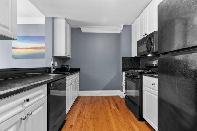 kitchen with white cabinetry, dark countertops, a sink, and black appliances