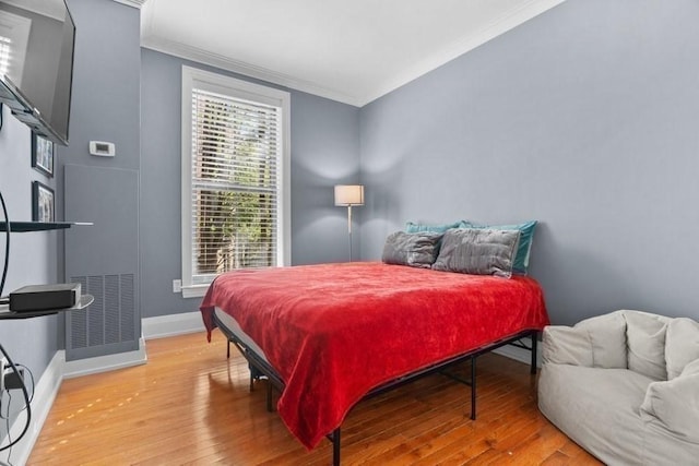 bedroom featuring crown molding, baseboards, and wood finished floors