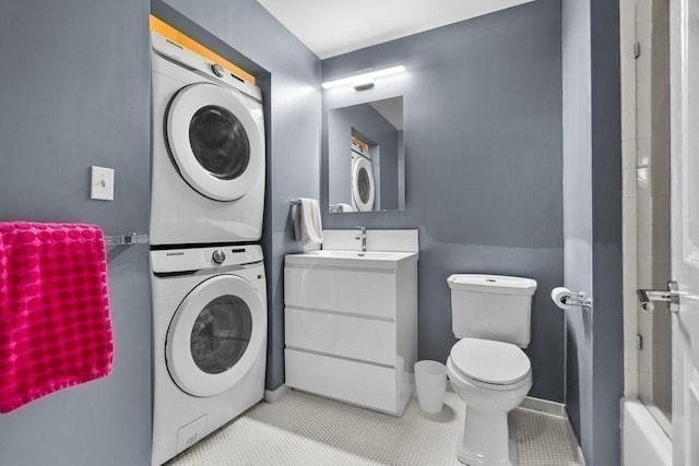 bathroom featuring a shower, tile patterned floors, vanity, toilet, and stacked washer and clothes dryer