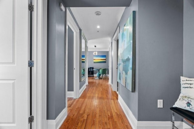 hallway with crown molding, baseboards, and light wood-type flooring