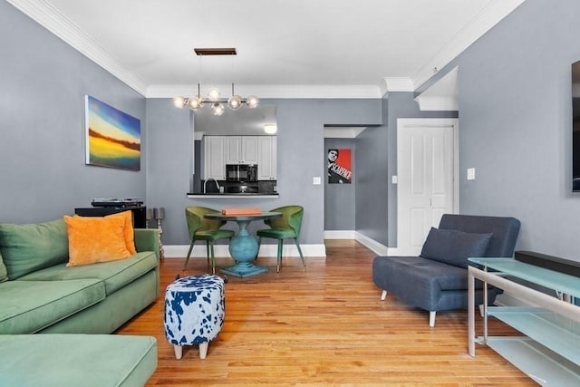 living room with crown molding, baseboards, a notable chandelier, and light wood-style flooring