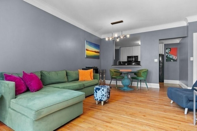 living room featuring crown molding, baseboards, an inviting chandelier, and light wood finished floors
