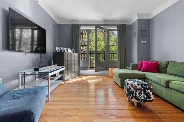 living area with ornamental molding, hardwood / wood-style floors, and visible vents